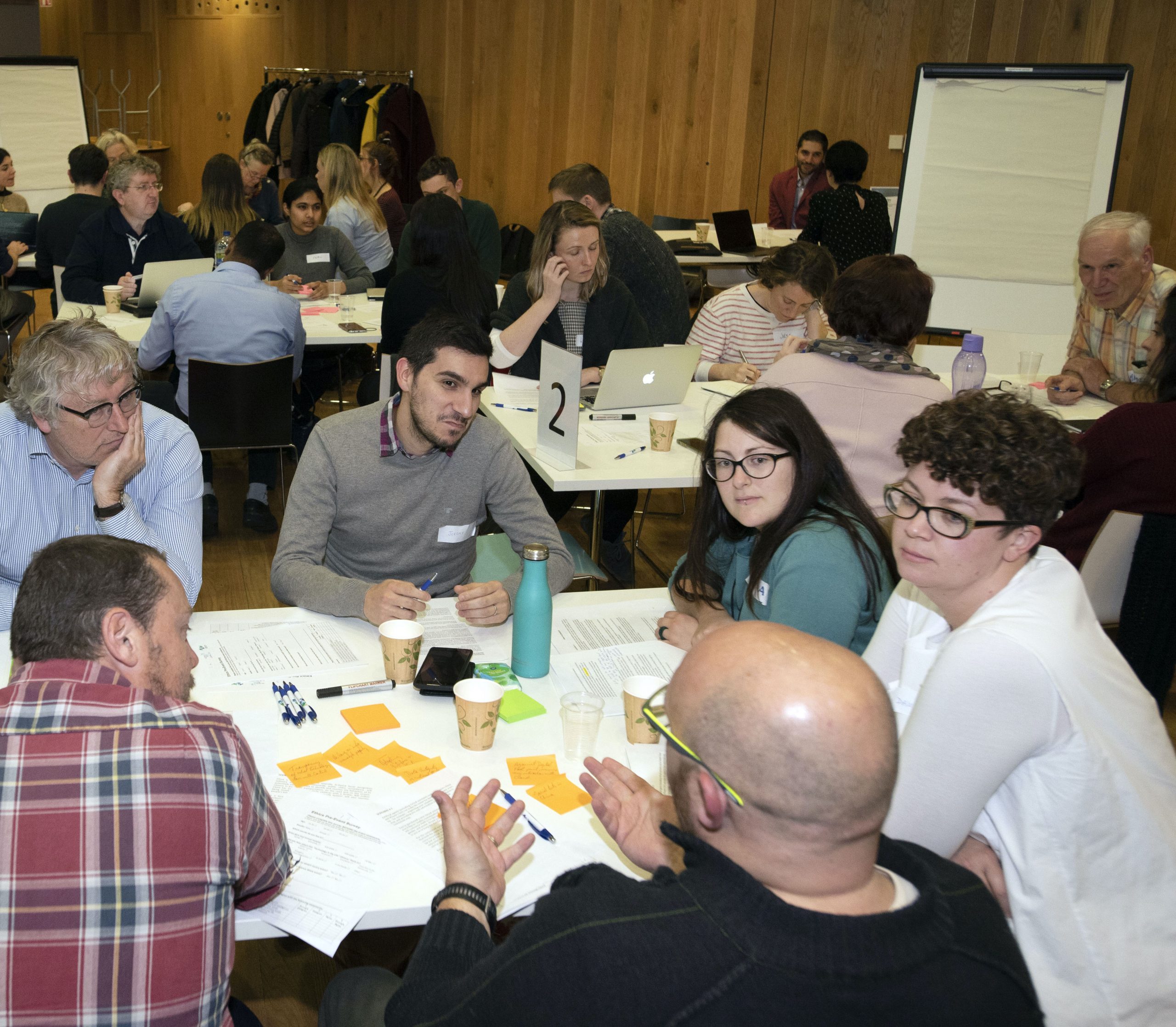 A group of adults sitting around a table at a public event, deep in discussion