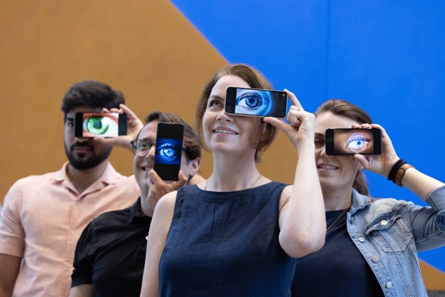 Four People holding a phone each over their left eye with an image of an eye on each of their screens
