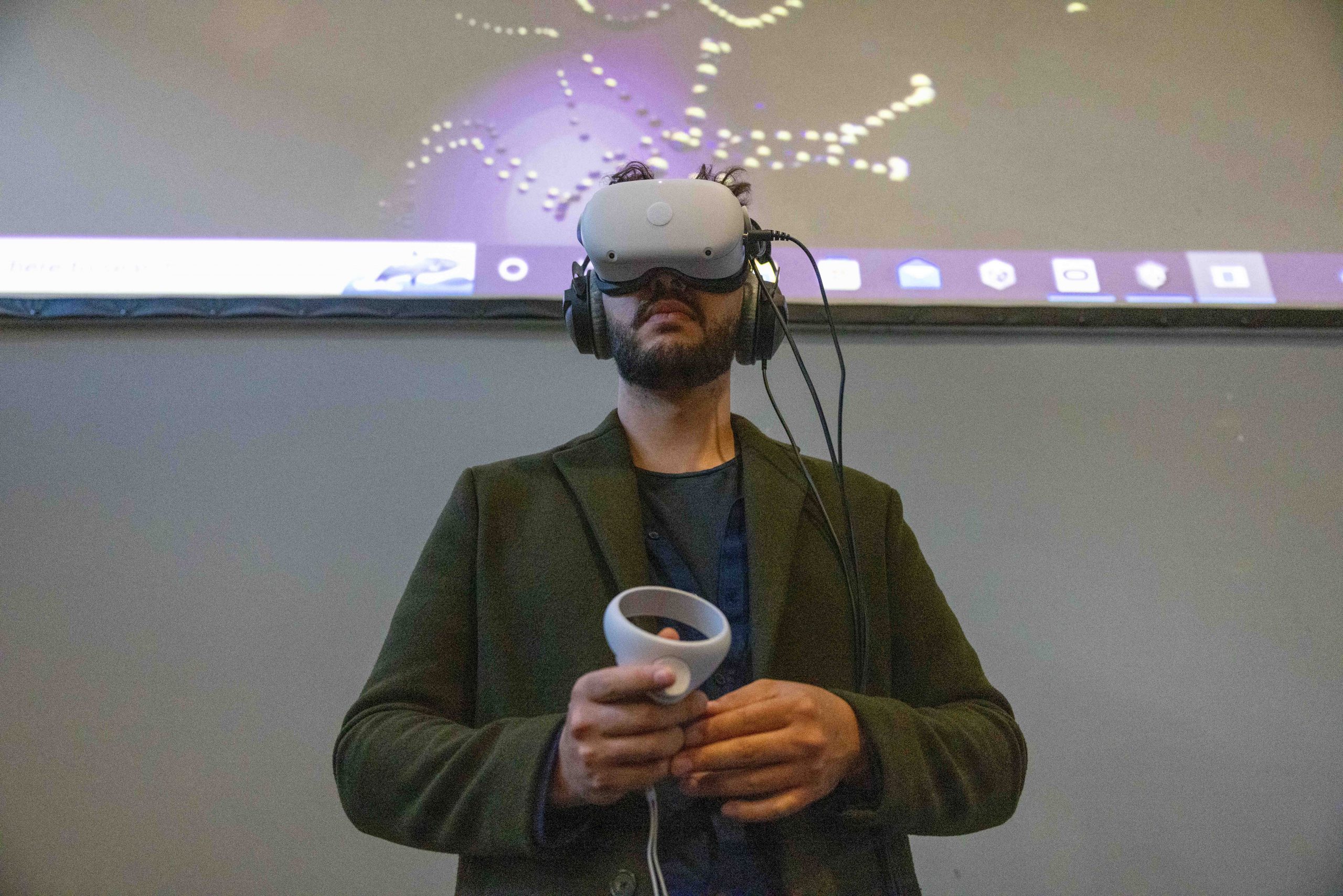 man wearing a virtual reality headset, holding a controller, looking upwards
