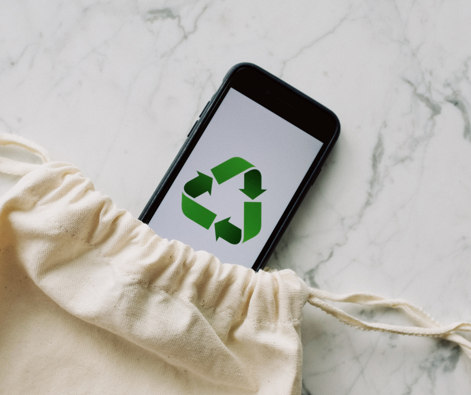 A phone sticking out of a cotton tote bag with the "Reduce Recycle Reuse" logo on the screen