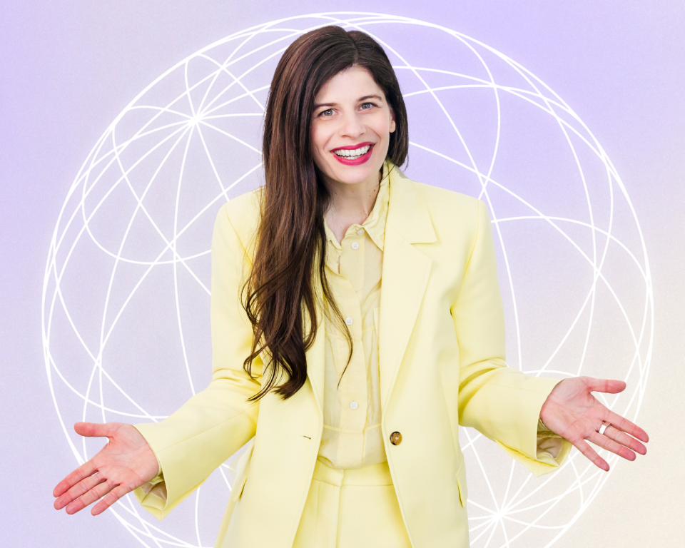 A woman with long brown hair, wearing a yellow suit standing with arms open in front of a lilac background