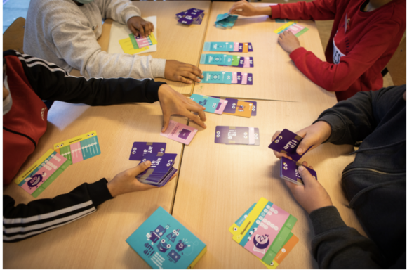 Close-up photo of young students' hands while playing amai! card game