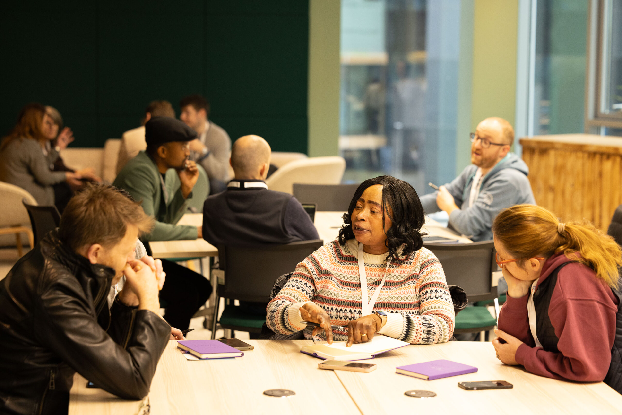 Teachers chat animatedly while sitting at a discussion table at an AI Literacy in the Classroom workshop